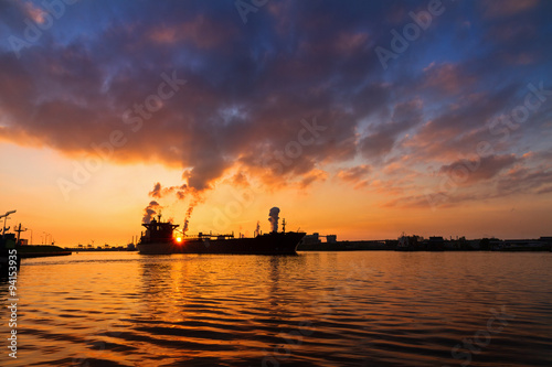 Silhouette of a big cargo ship and industry at sunset in IJmuiden in the Netherlands