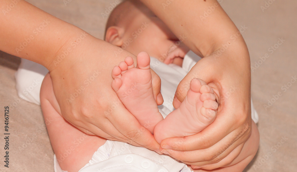 newborn baby feet on female hands, shape like a lovely heart newborn baby feet on female hands, shape like a lovely heart