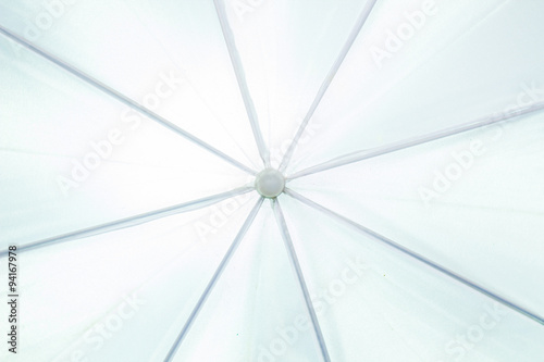 Abstract image of closeup to center of white umbrella with light on the back.