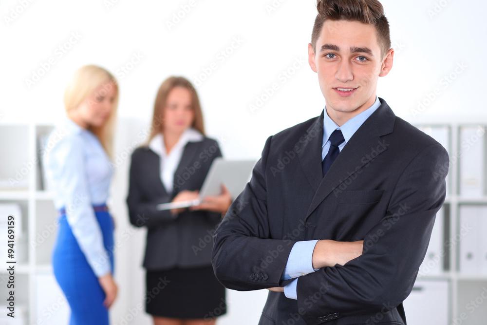 Cheerful business man in office with colleagues in the background, sturt-up team Cheerful business man in office with colleagues in the background, sturt-up team