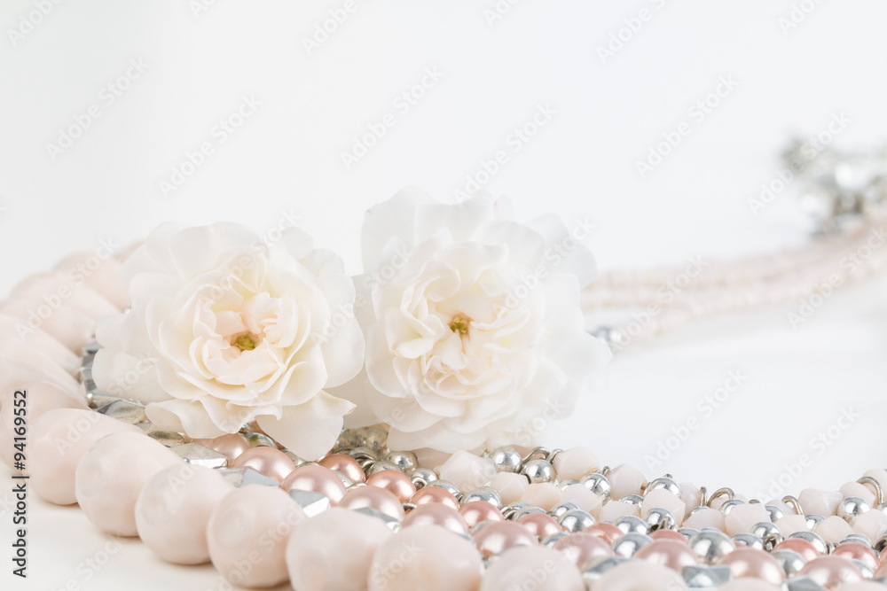 Close up of pastel pink beaded necklace with miniature rose flowers. Soft pastel dreamy photograph.