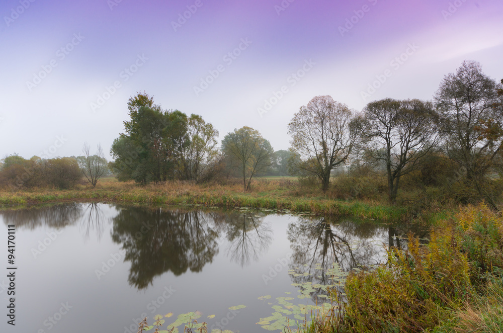 Early morning view of calm lake surrounded by trees