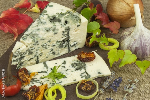 Cheese with mold on a wooden cutting board. Preparation of aromatic cheese. Stilton cheese on wooden cheese board. Slices of Danish Blue cheese on an table. 
