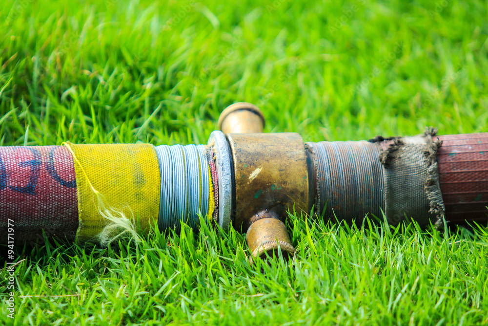 Fototapeta premium Fire hose on the green grass.