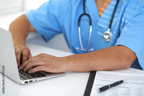 Portrait of unknown male surgeon doctor with laptop holding his stethoscope