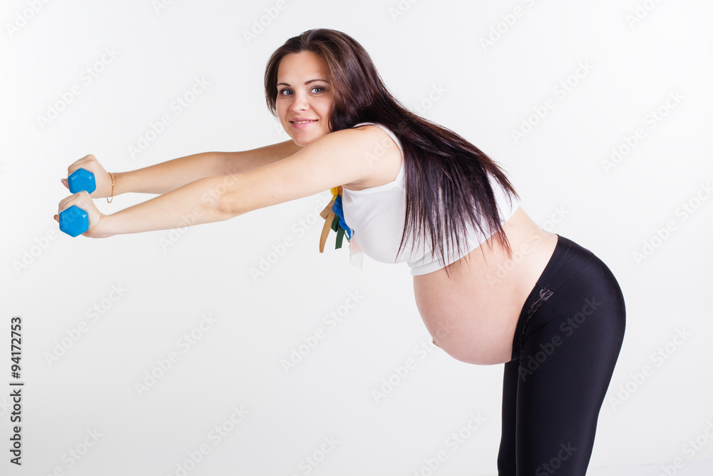 Pregnant woman exercising back with dumbbells Pregnant woman exercising back with dumbbells