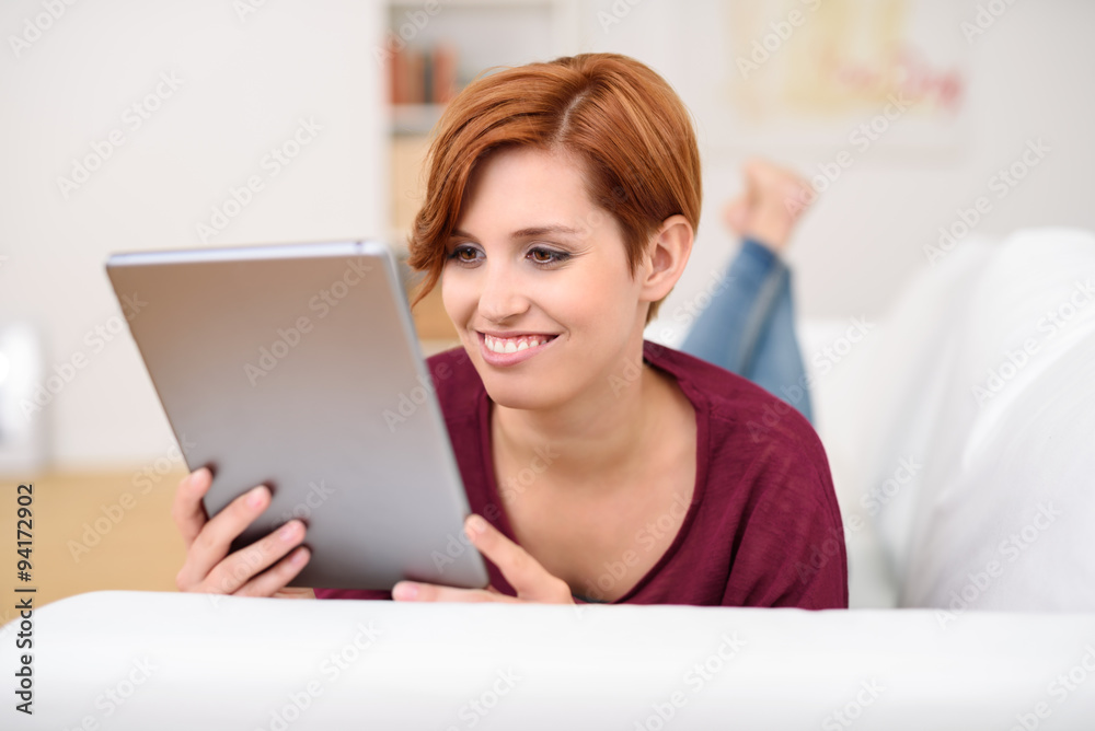 lächelnde junge frau liest am tablet-pc lächelnde junge frau liest am tablet-pc