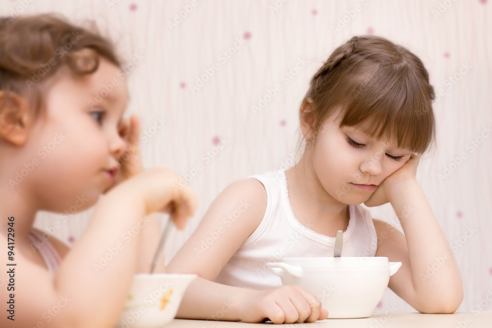 Two pretty little girls eating without appetite Two pretty little girls eating without appetite