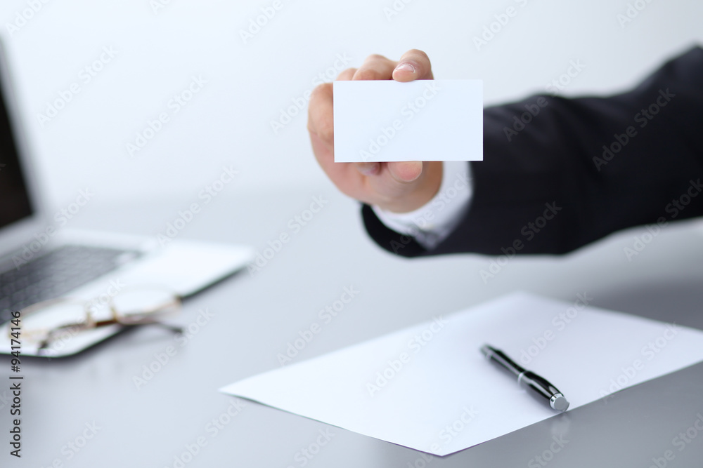 Close-up of businessman giving a business card, sitting at the table Close-up of businessman giving a business card, sitting at the table