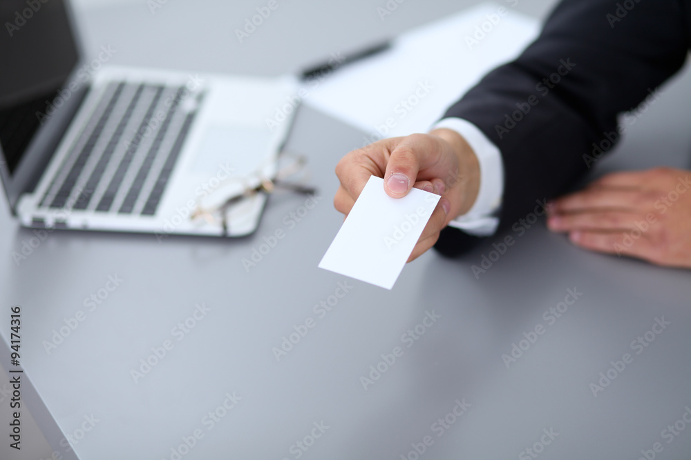 Close-up of businessman giving a business card, sitting at the table Close-up of businessman giving a business card, sitting at the table