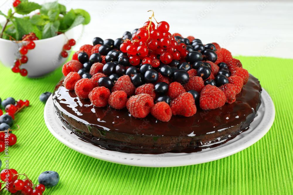 Delicious chocolate cake with summer berries on green tablecloth, closeup Delicious chocolate cake with summer berries on green tablecloth, closeup