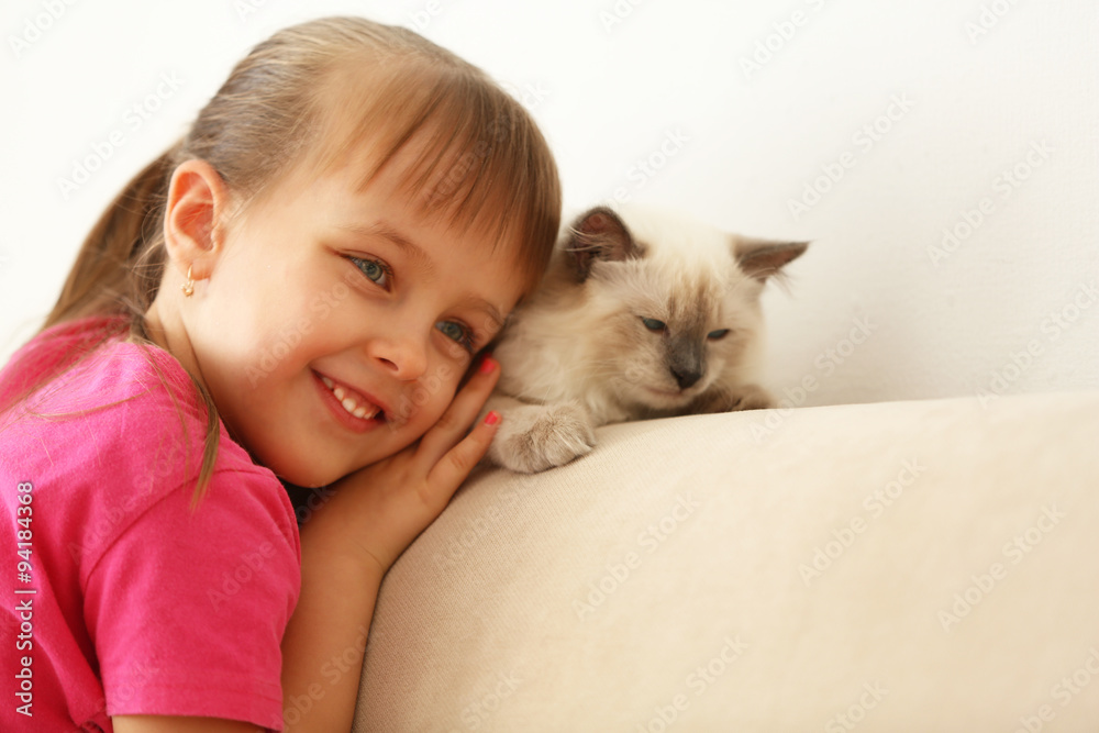 Little cute girl with kitten on sofa at home Little cute girl with kitten on sofa at home