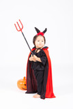 devil girl in black suit and red cape  with halloween pumpkin an