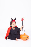 devil girl in black suit and red cape  with halloween pumpkin an