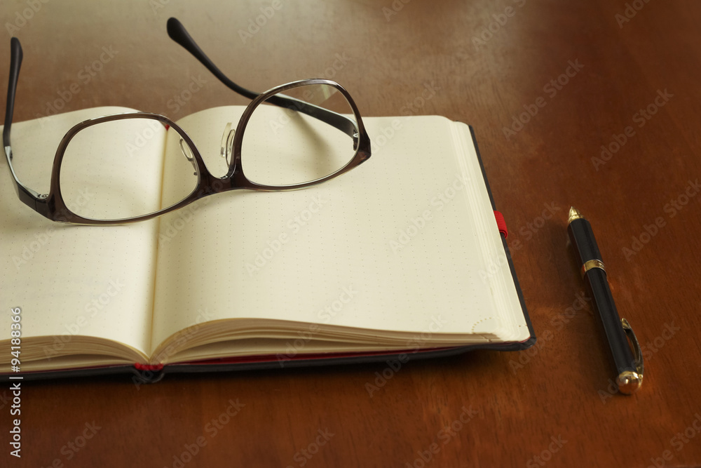 Reading glasses and schedule book and pen Reading glasses and schedule book and pen
