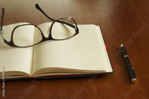 Reading glasses and schedule book and pen