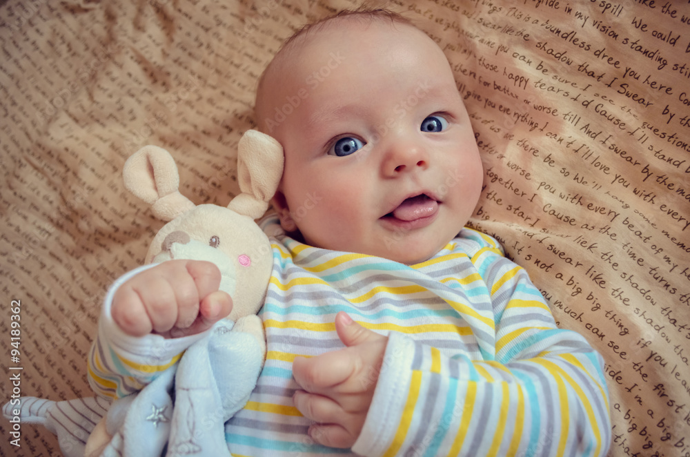 Beautiful baby hags a toy mouse and shows tongue Beautiful baby hags a toy mouse and shows tongue
