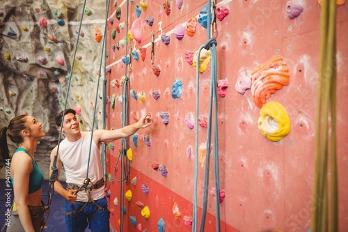 Instructor showing woman rock climbing wall