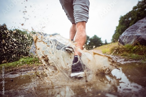 Valokuva Man jogging through muddy puddles