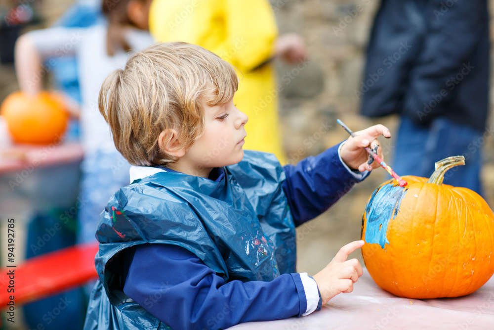 Fototapeta premium Little kid boy painting with colors on pumpkin