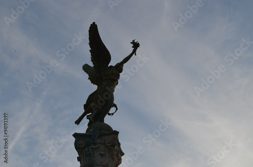 Statue of angel on a pillar against sky