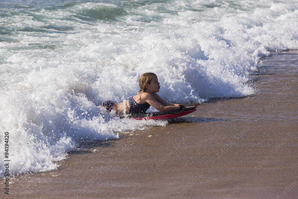 Girl surfing body board rides wave onto beach Girl surfing body board rides wave onto beach