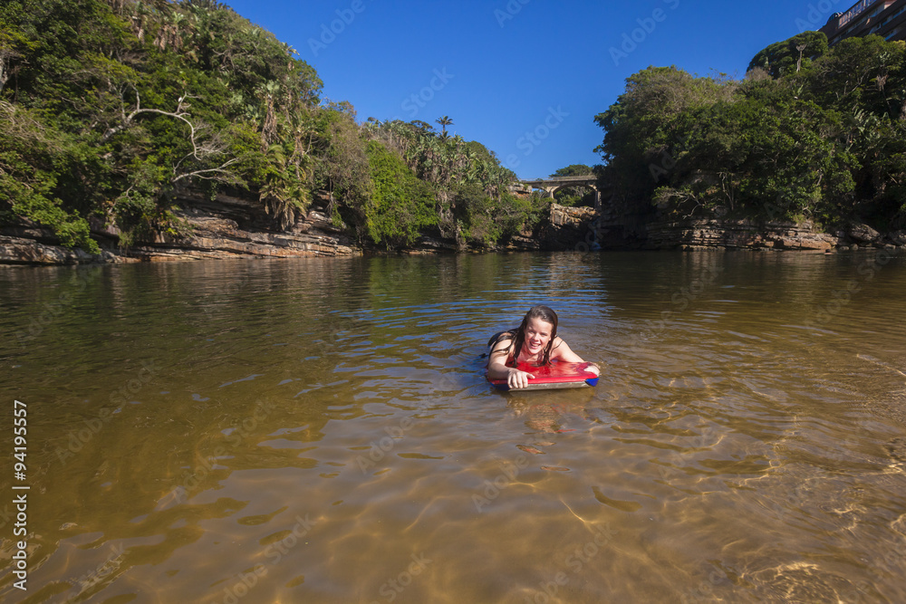 Girl swimming with board in river beach lagoon