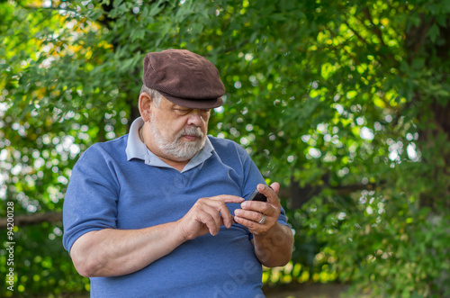 Portrait of bearded senior man using cellular phone outdoor