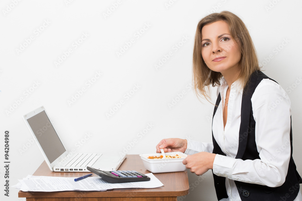 girl eats a pasta, working behind the laptop.