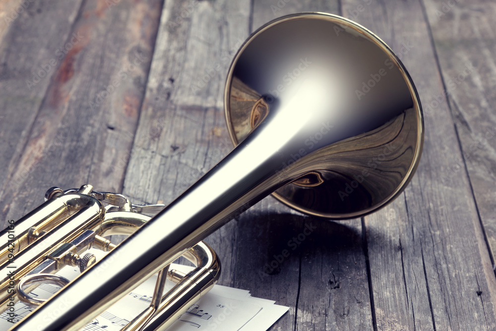 Obraz premium Trumpet and sheet music on old wooden table. Vintage style.