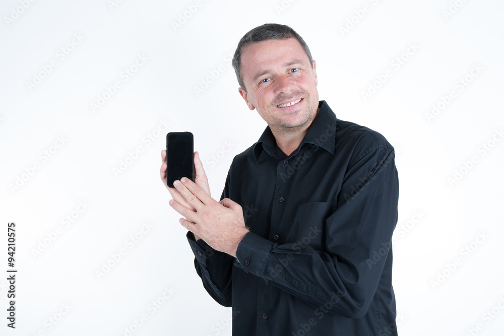 Copy space on his telephone. Cheerful man showing mobile phone and smiling while standing against white background