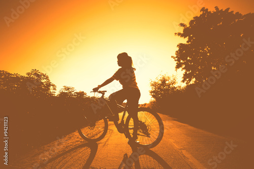 silhouette of woman at sunset with bicycle and happy