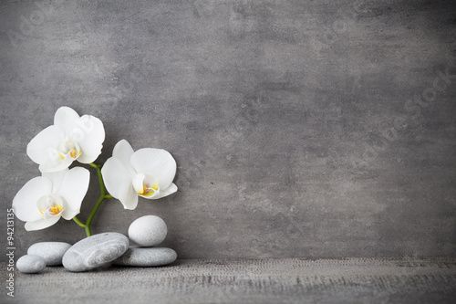 White orchid and spa stones on the grey background.