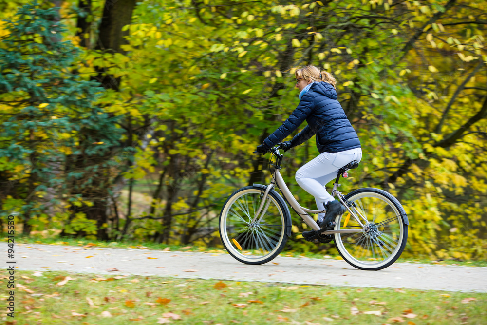 Fototapeta premium Urban biking - woman riding bike in city park 