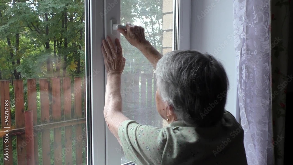 Elderly Woman opens a window Elderly Woman opens a window