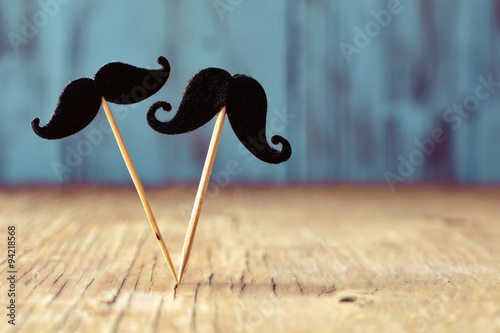 felt mustaches in sticks on a wooden surface photo