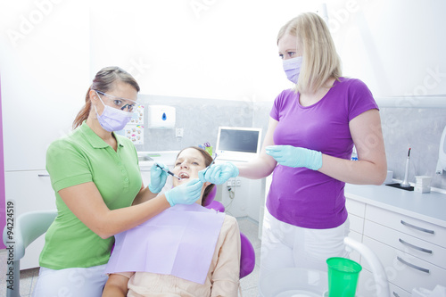 Female dentist working on teeth of women and her female assistan