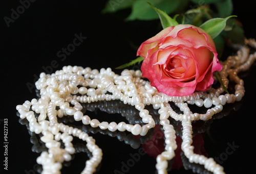 pink rose and perls reflecting i black surface