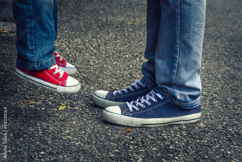 Children and adults legs in sneakers. Father lifted the child up