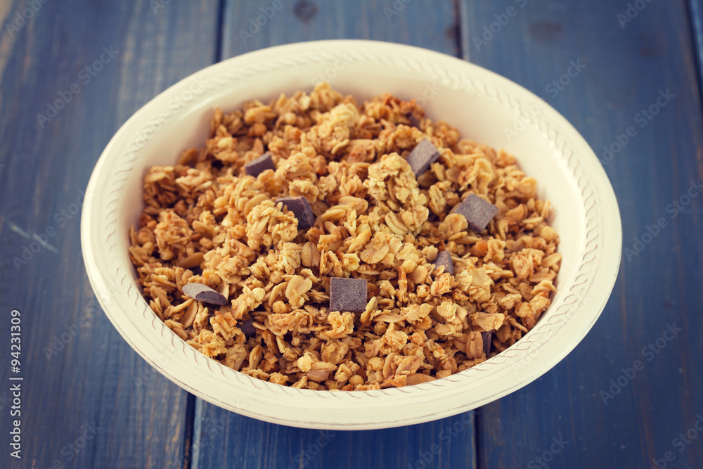 granola on white bowl on blue wooden background granola on white bowl on blue wooden background