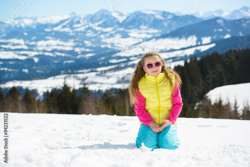 Smiling little girl in sunglasses  in winter mountains on a sunny day © oksanatrautwein