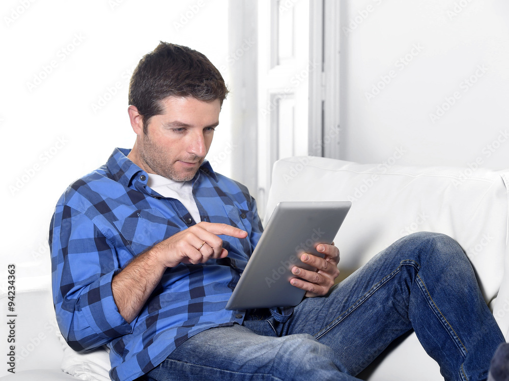 young attractive 30s man using digital tablet pad lying on couch at home networking looking relaxed young attractive 30s man using digital tablet pad lying on couch at home networking looking relaxed