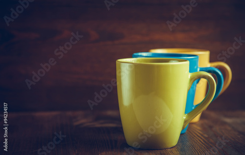 Color cups at the wooden background, toned