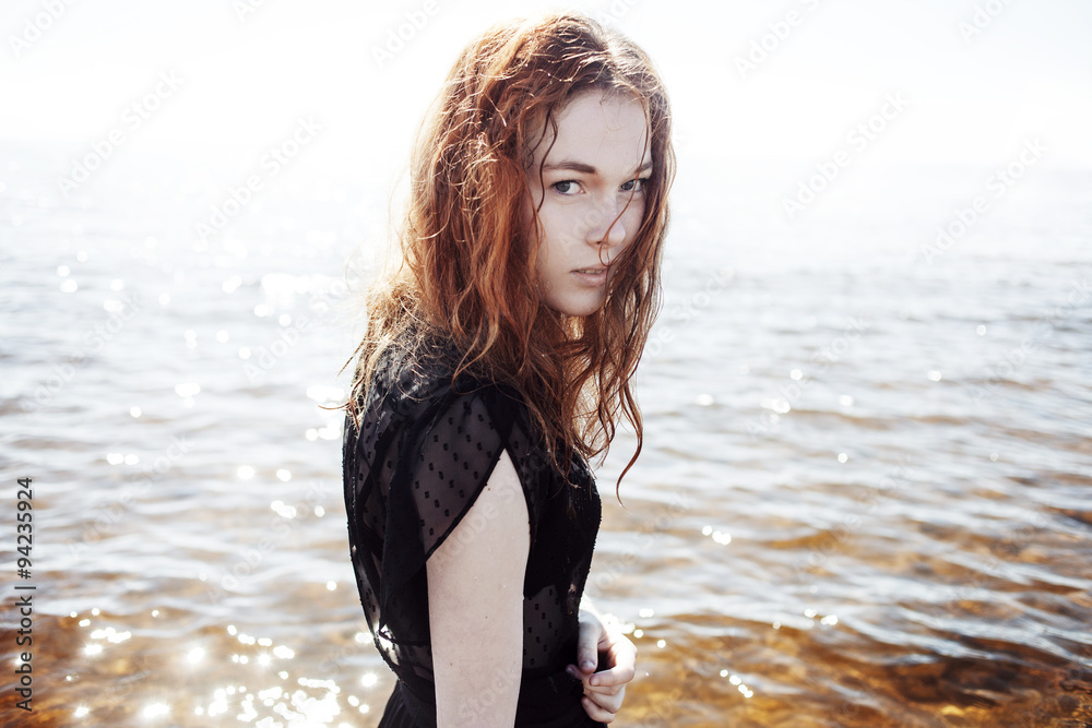 Young redhead woman outdoors portrait on background of the sea Young redhead woman outdoors portrait on background of the sea