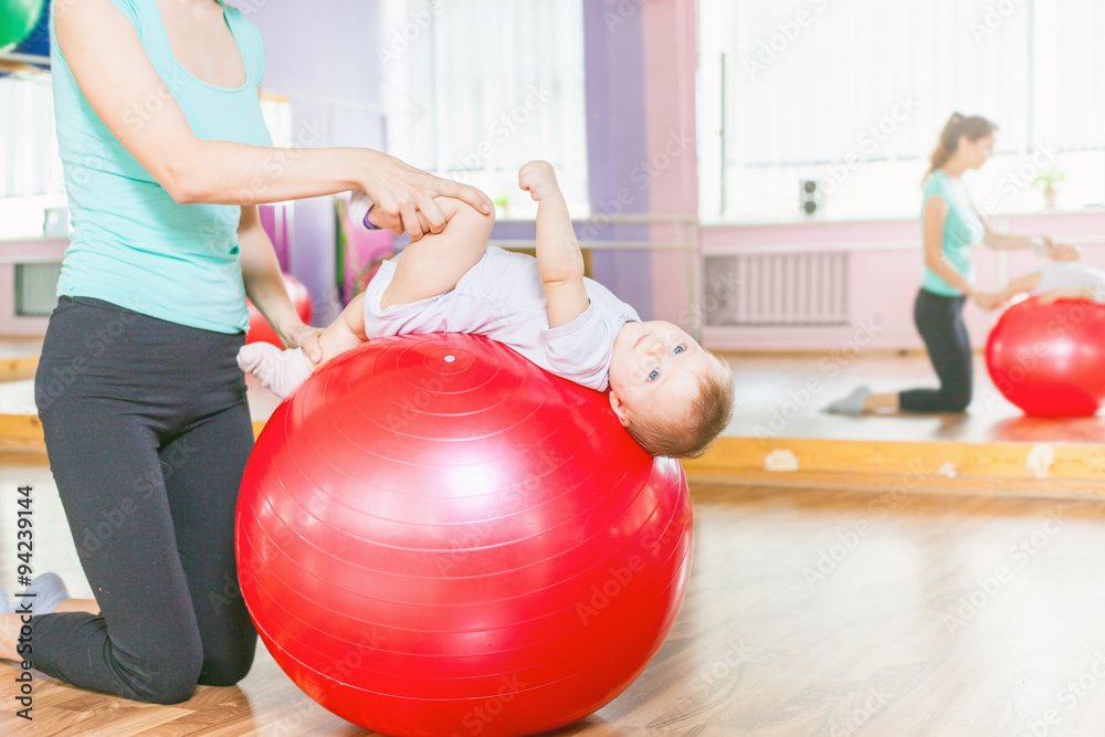 Naklejka premium Mother with happy baby doing exercises with gymnastic ball