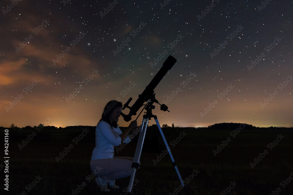 Woman looking through a telescope watching the stars.. Night sky