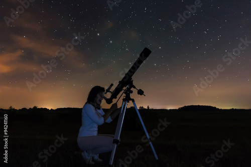 Tableau sur Toile Femme regardant à travers un télescope regarder les étoiles du ciel