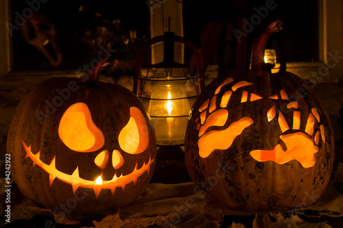 Photo composition from two pumpkins on Halloween. Jack and awful hands against an old window, dry leaves and a terrible ghost in a window