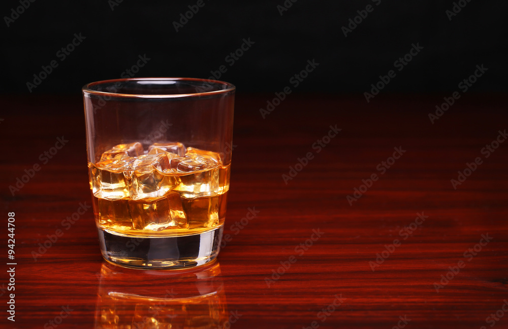 Glass of alcohol scotch whiskey with ice cube on wooden table an Glass of alcohol scotch whiskey with ice cube on wooden table an