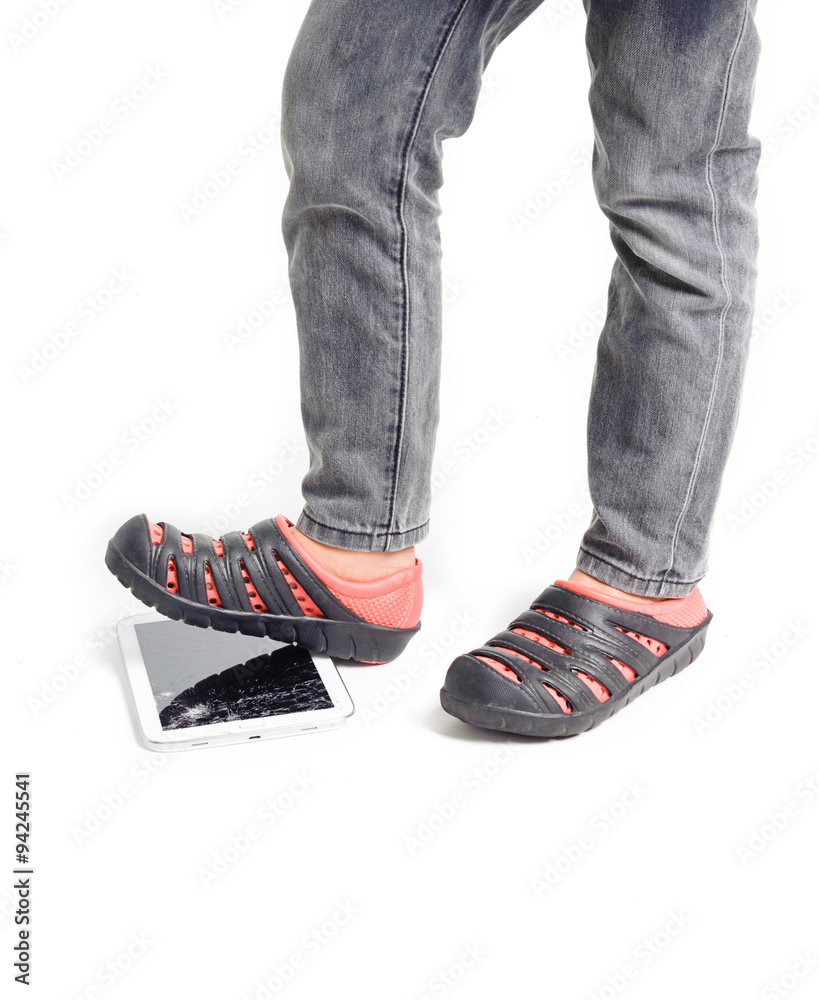 Boy feet step over on broken tablet on white background Boy feet step over on broken tablet on white background